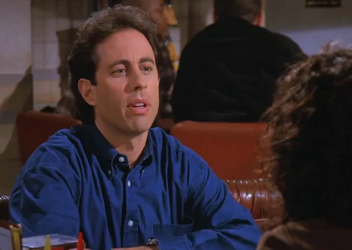 Jerry from Seinfeld wearing a blue shirt, captured in a classic scene reflecting funniest Seinfeld quotes about everyday life.