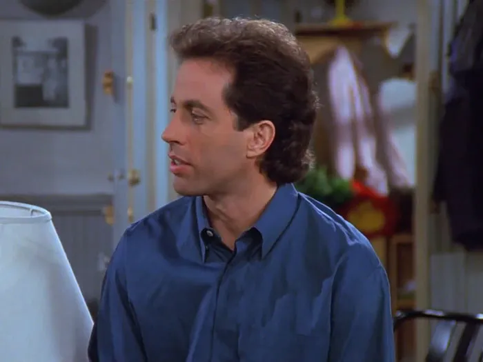 Jerry wearing a blue shirt in a classic scene from Seinfeld, featuring some of the funniest Seinfeld quotes about everyday life.