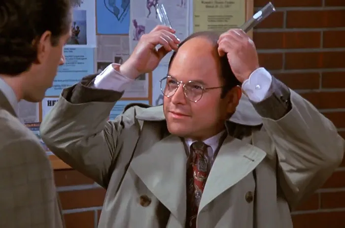George wearing a gray jacket making a humorous gesture, capturing the funniest Seinfeld quotes about everyday life.