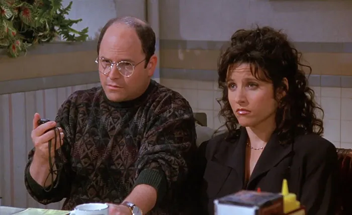 George wearing a brown colorful sweater sitting next to a woman, representing funniest Seinfeld quotes about everyday life.