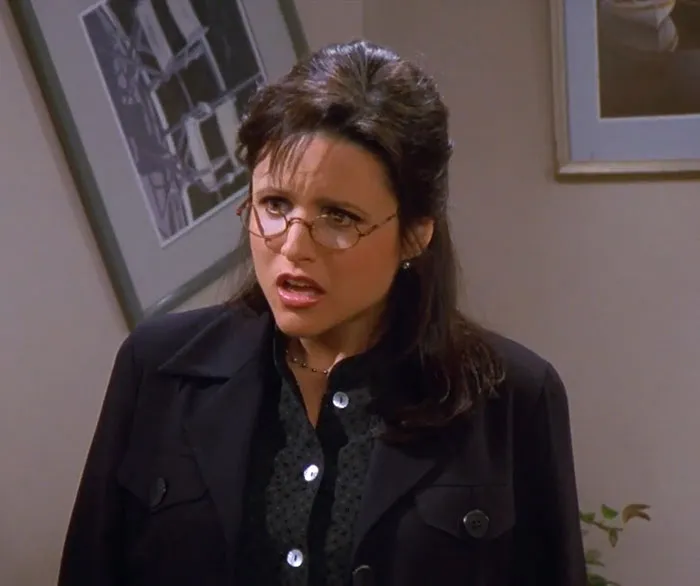 Elaine in a black jacket with glasses, expressing surprise in a scene featuring funniest Seinfeld quotes about everyday life