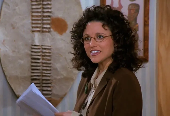 Elaine from Seinfeld wearing brown jacket and yellow shirt, illustrating funniest Seinfeld quotes about everyday life moments