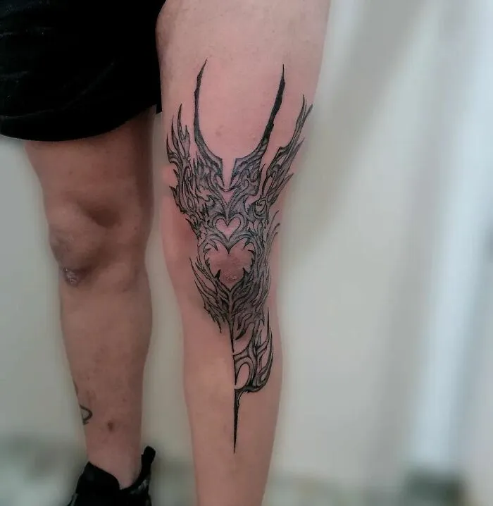 Leg with intricate tribal tattoo design, showcasing bold black patterns on skin.