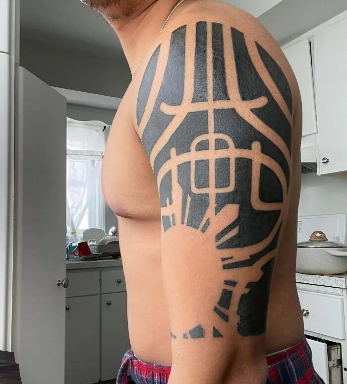 Arm with a tribal tattoo design showing bold black patterns in a kitchen setting.