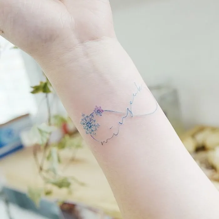 Delicate infinity tattoo on wrist featuring blue floral design, symbolizing eternal creativity.