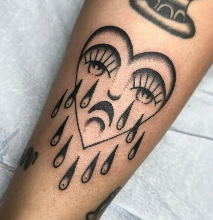 American traditional tattoo design featuring a sad face with tears on skin.