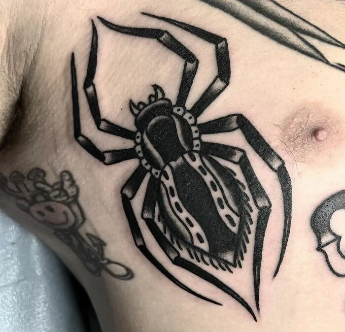 American traditional tattoo of a black spider on a person's skin.