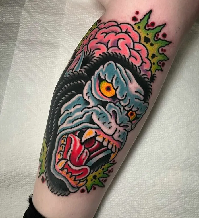 American traditional tattoo featuring a colorful, fierce monster design on forearm skin.