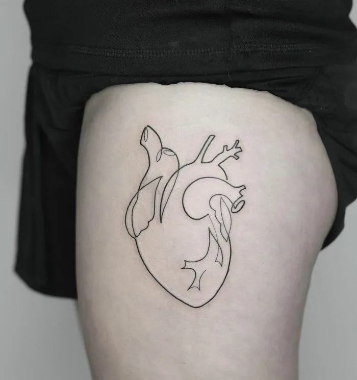 Fine-line single-line tattoo of an anatomical heart on skin.