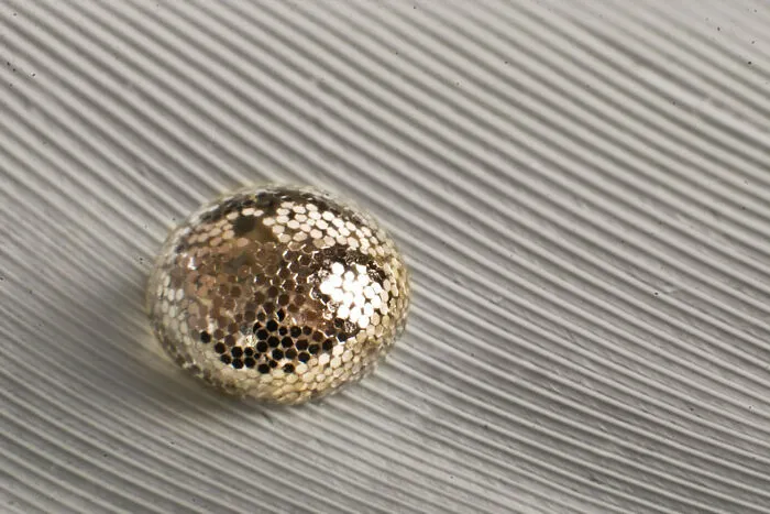 ITAP Of A Glitter-Coated Waterdrop Sitting On A Feather