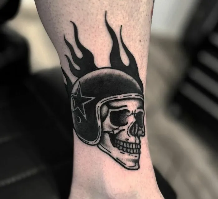 American traditional tattoo of a skull with a flaming helmet and star design on the arm.