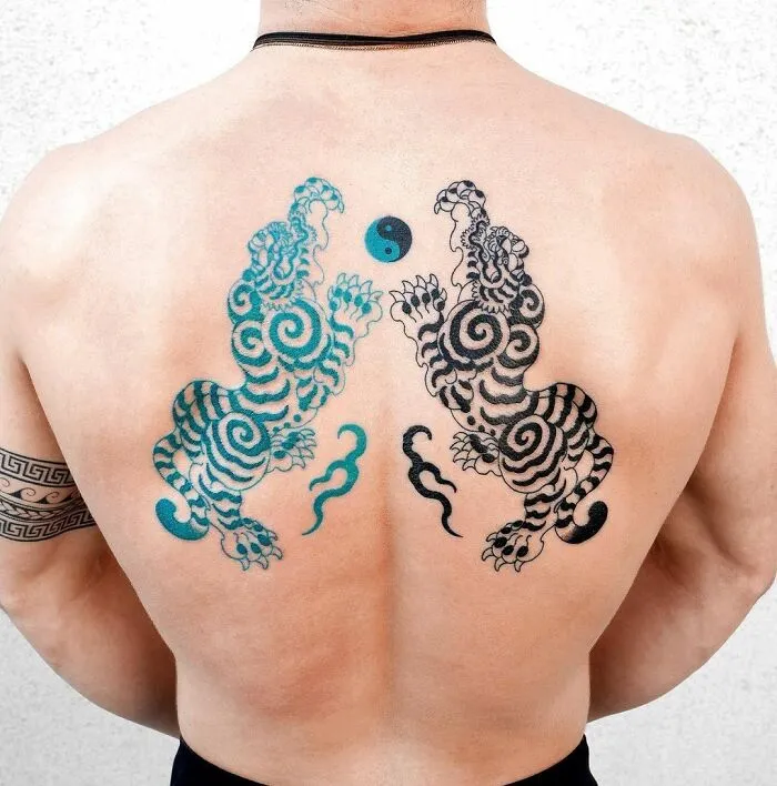 Back tattoo of artistic yin yang with vibrant swirling tigers.