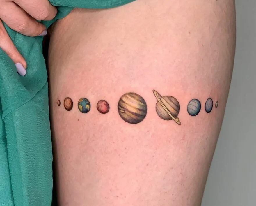 Solar system tattoo featuring planets in a line on skin, showcasing outer space cool design.