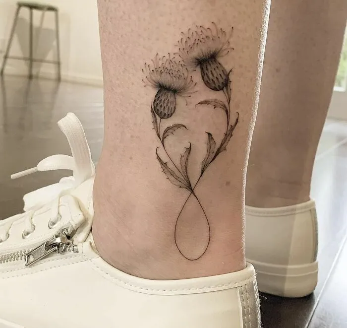 Infinity tattoo with floral design on ankle, showcasing eternal creativity.