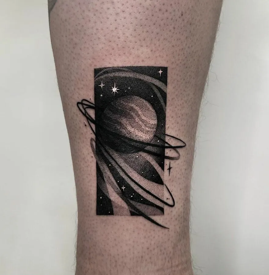 Tattoo of a planet with orbiting rings and stars, showcasing outer space cool art on skin.