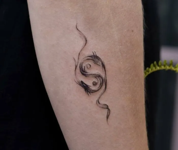Abstract yin yang tattoo with flowing lines on forearm, symbolizing the duality of life.