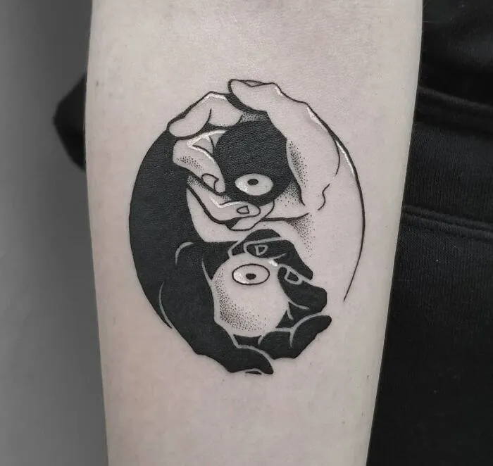 Yin Yang tattoo featuring two hands with dots, illustrating duality and harmony.