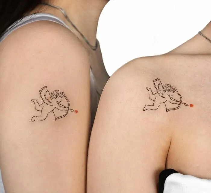 Matching cupid tattoos on friends' arms, symbolizing friendship with heart-tipped arrows.
