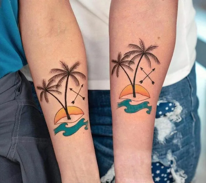 Matching palm tree arm tattoos depicting friendship with arrows and sunset.