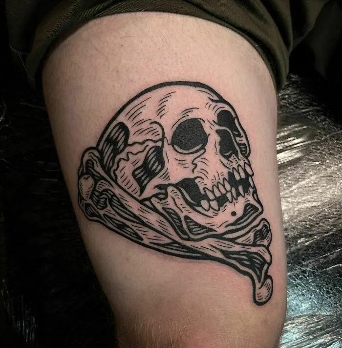 Gothic tattoo featuring a detailed skull and bones design on the upper arm.