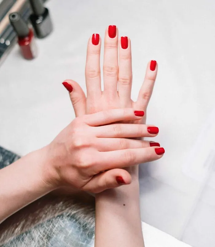 Hands with red nail polish shown in a close-up, illustrating unique style for 40 useless facts to impress friends.