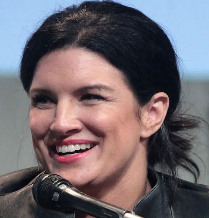 Gina Carano, an actor who had an amazing career, laughs while speaking into a microphone.