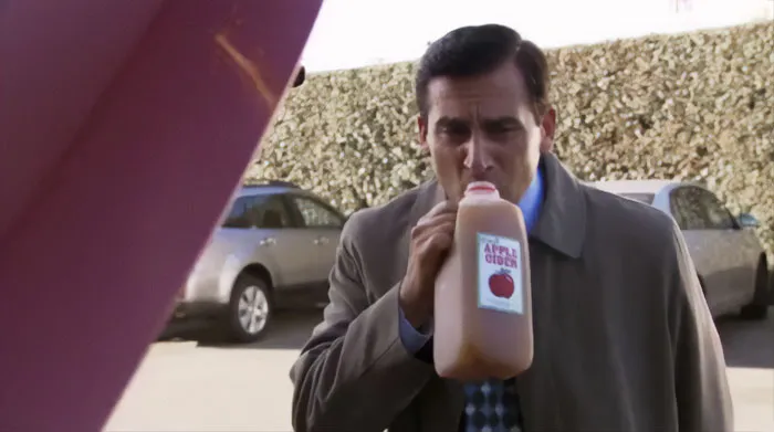 Michael Scott drinking apple cider outdoors in a coat, showcasing memorable Michael Scott quotes about being the best boss.
