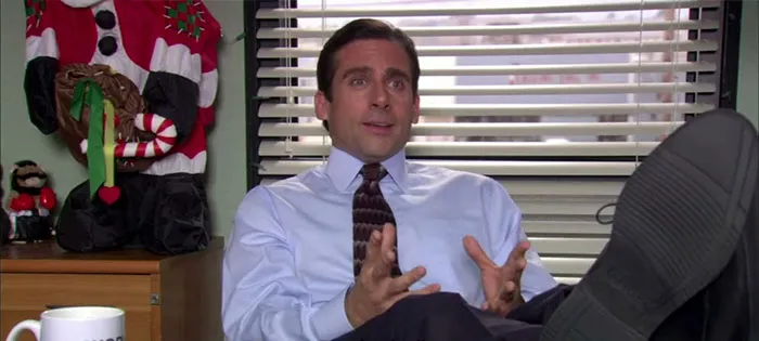 Michael Scott talking with his feet on the table, demonstrating why he's considered the best boss ever in iconic quotes.