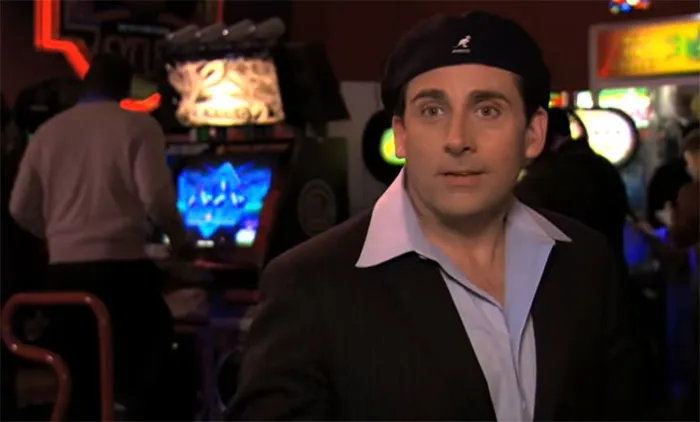 Michael Scott as Date Mike in a black suit and backwards cap at an arcade, showcasing his best boss personality.