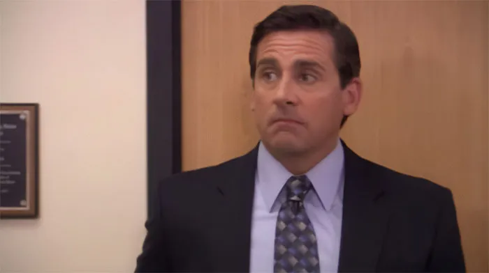 Michael Scott raising eyebrows in an office setting, showcasing qualities of the best boss with memorable quotes.