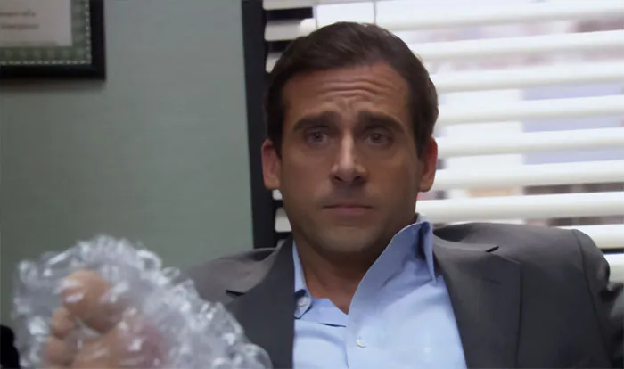 Michael Scott sitting in office with broken foot wrapped in ice pack, showcasing memorable Michael Scott quotes.