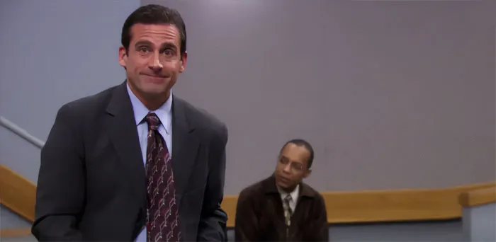 Michael Scott smiling in a suit and tie, showcasing the best boss ever attitude in an office setting.