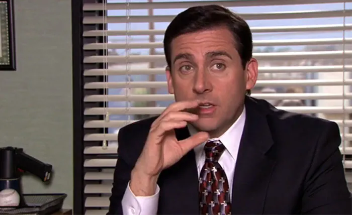Michael Scott in a suit and tie talking in an office setting, illustrating iconic Michael Scott quotes about leadership.