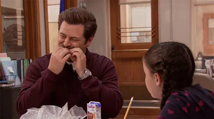 Ron Swanson eating a sandwich at a table, illustrating moments for Ron Swanson quotes about life and wisdom.