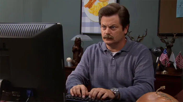 Ron Swanson typing on a computer, focused expression, representing Ron Swanson quotes about life and wisdom.