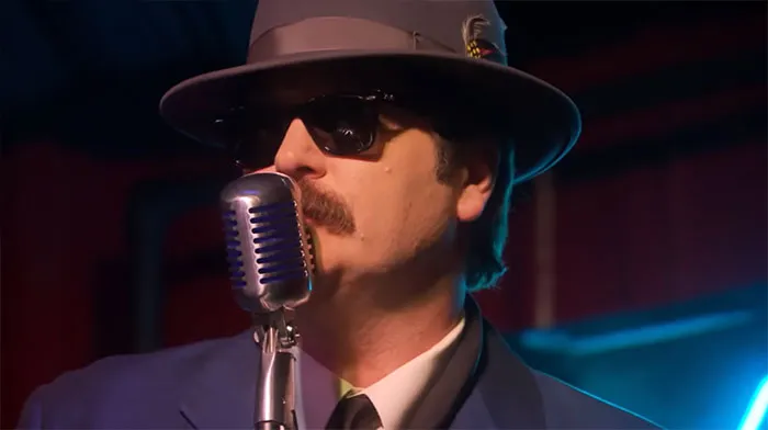 Ron Swanson wearing sunglasses and a hat, singing into a vintage microphone on stage, capturing Ron Swanson quotes spirit.