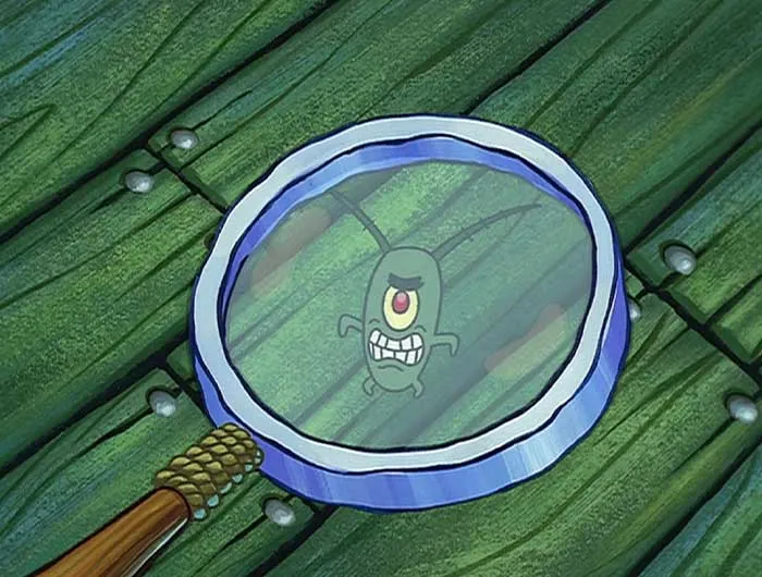Plankton from SpongeBob looking angrily through a magnifying glass on a green wooden floor background.