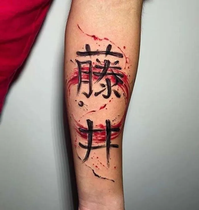 Family tattoo with bold black calligraphy and red swirls on forearm.