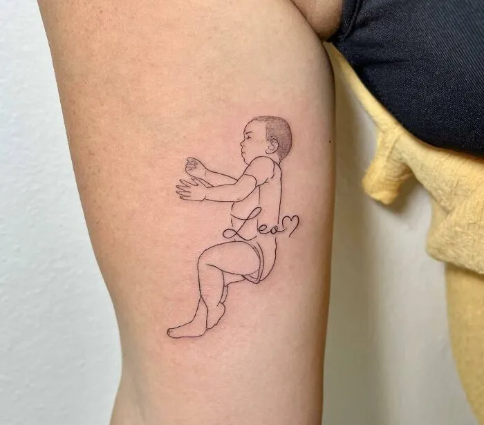 Tattoo of a baby with the name "Leo" symbolizing family bonds, inked on an arm.