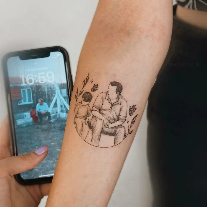 Tattoo of a father and child, symbolizing family bonds, next to a matching photo displayed on a smartphone screen.