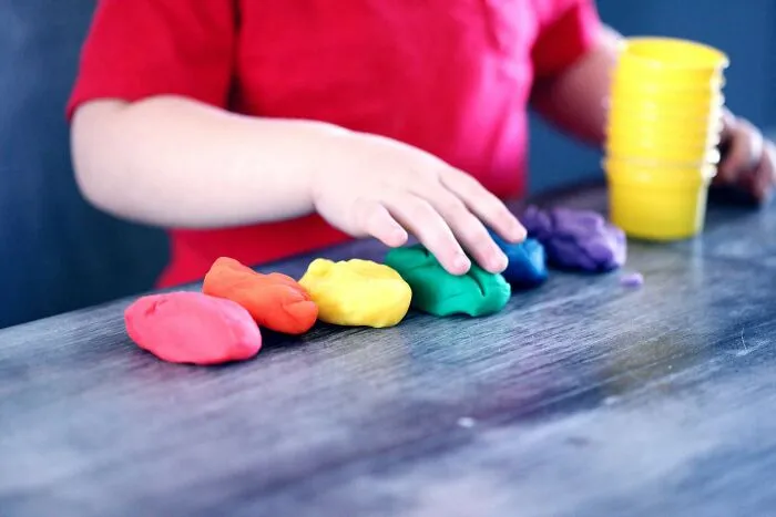A young person creating colorful modeling clay figures, a fun activity perfect for sharing useless facts.