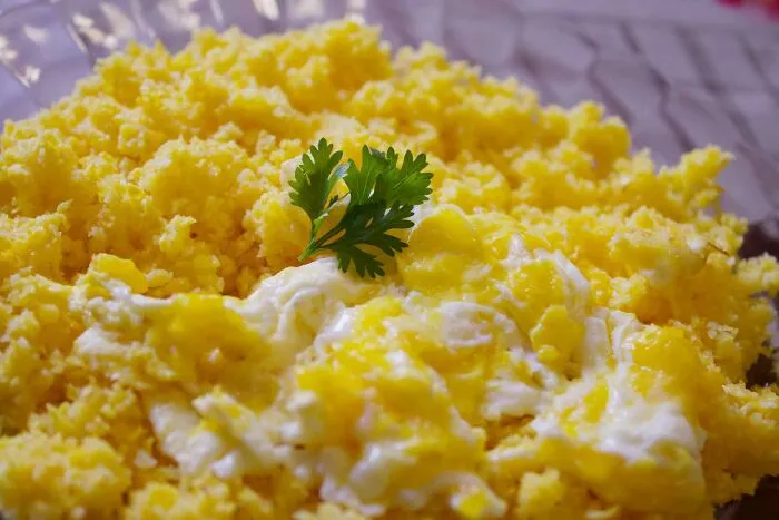 Close-up of fluffy scrambled eggs garnished with a fresh parsley leaf, perfect for sharing 40 useless facts to impress friends.