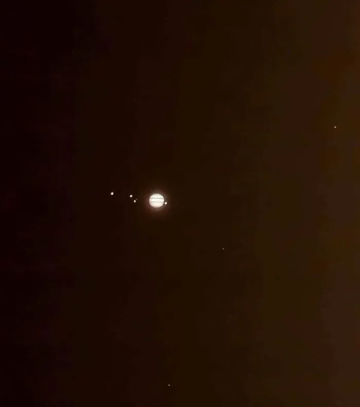 Jupiter And Its 4 Largest Moons Glowing In The Night-Sky. Ganymede, Europa, And Callisto On The Left, Io On The Right Side