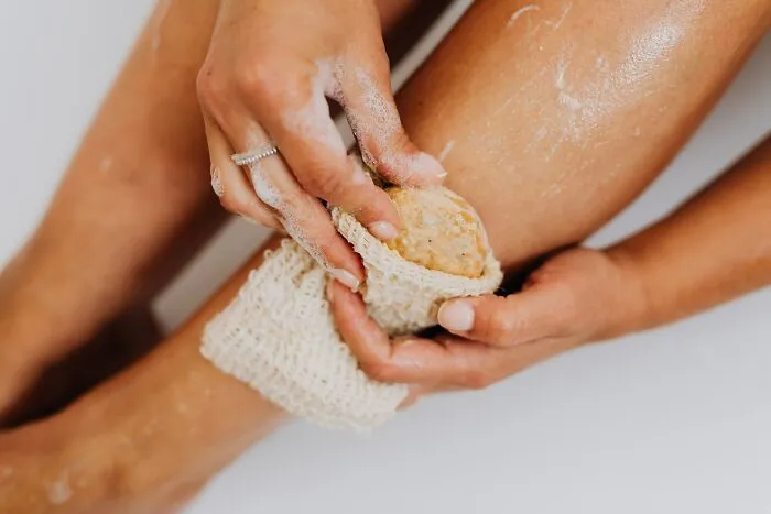 Woman Using Loofah To Scrub Her Legs 