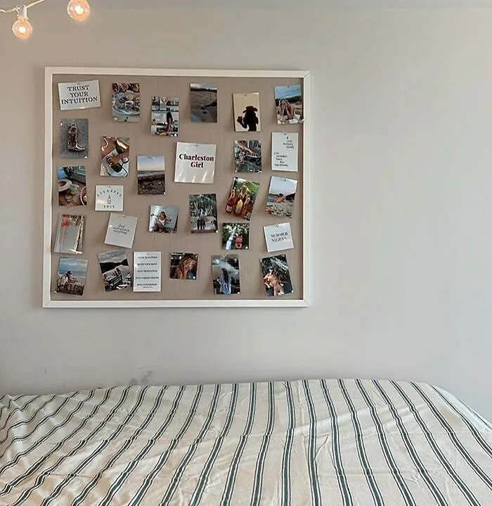 Wall-mounted pinboard with photos and notes above a striped bed, showing creative bedroom wall decor ideas.