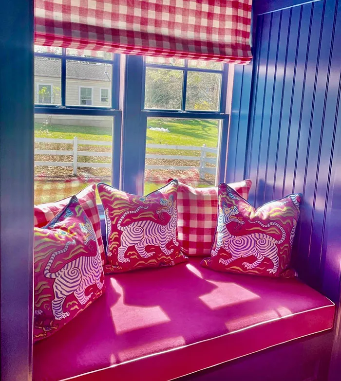 Colorful vibrant window seat with patterned pillows and checkered shades creating a cozy bright home space.