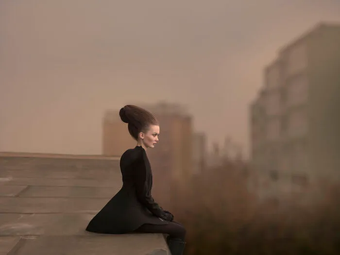 An image of a woman sitting at the edge of the roof