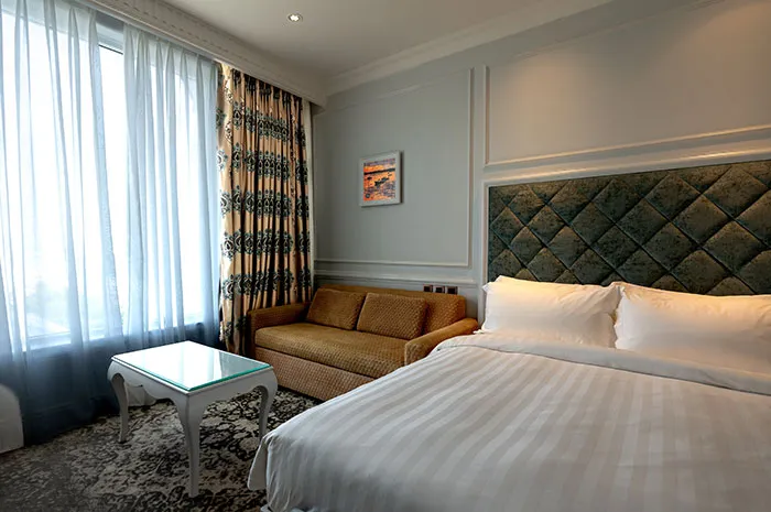 Bright bedroom interior featuring a white bed near a brown couch and table, showcasing stylish bedroom wall decor ideas.