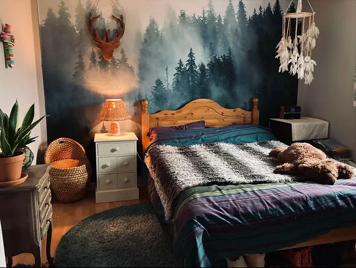 Bedroom featuring a forest accent wall with wooden bed, cozy bedding, nightstand, and stylish bedroom wall decor ideas.