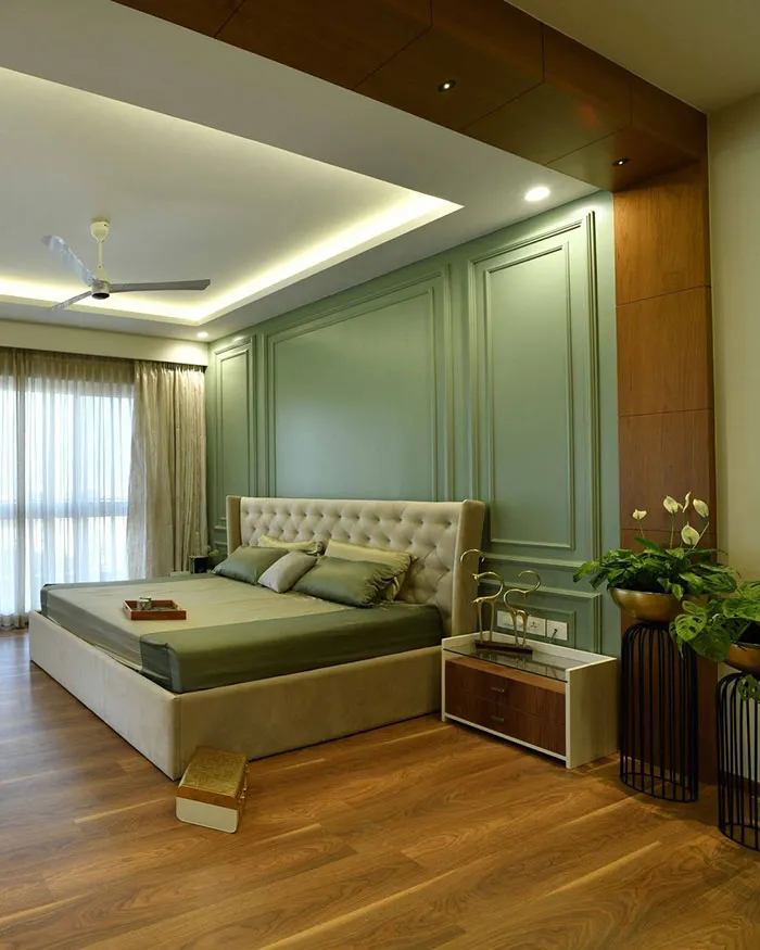 Cozy bedroom featuring a green moulded wall and modern bedroom wall decor ideas with natural light and plants.